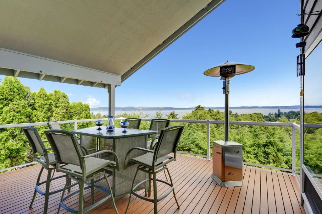 A beautiful outdoor deck with patio heater and outdoor furniture over the unobstructed view of wide lake